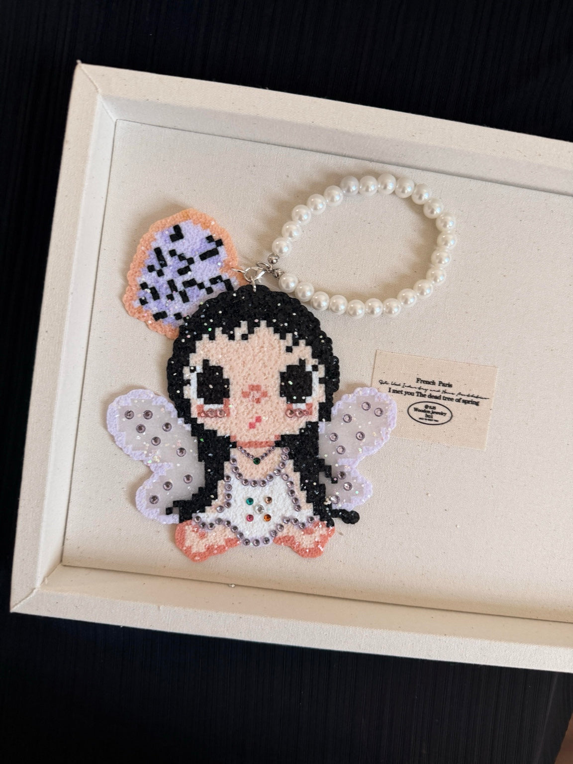 Handmade pixel bead charm featuring a seated fairy girl with lavender wings