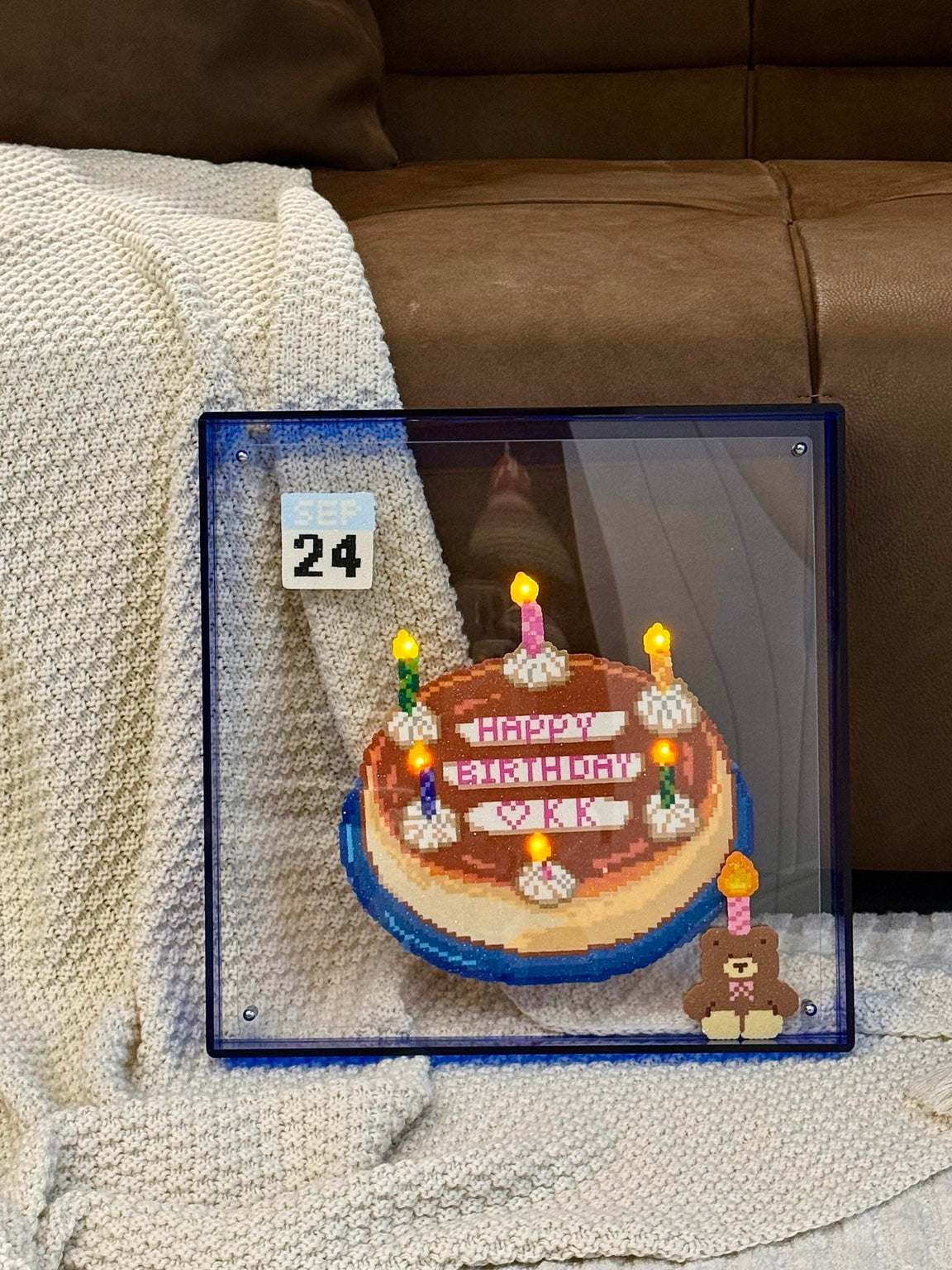 Handmade light-up birthday cake pixel bead frame displayed on a sofa