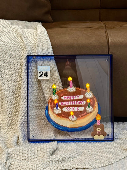 Handmade light-up birthday cake pixel bead frame displayed on a sofa