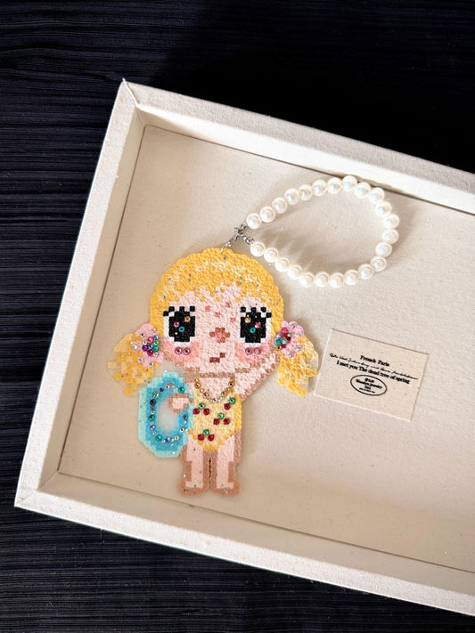Handmade pixel bead charm featuring a blonde girl with a blue bag and sparkling details