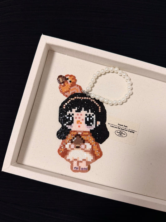 Handmade pixel bead charm featuring a girl in a brown bear-inspired outfit