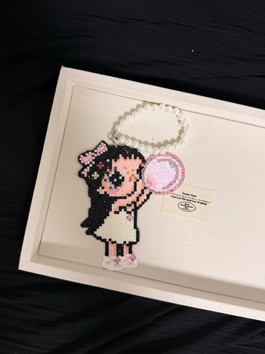 Handmade pixel bead charm featuring a black-haired girl blowing pink bubble gum