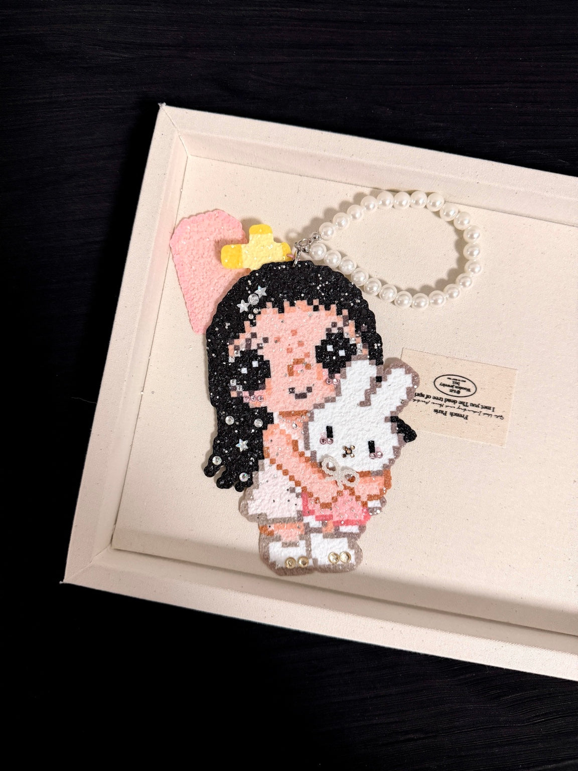 Handmade pixel bead charm featuring a pink girl holding a white bunny