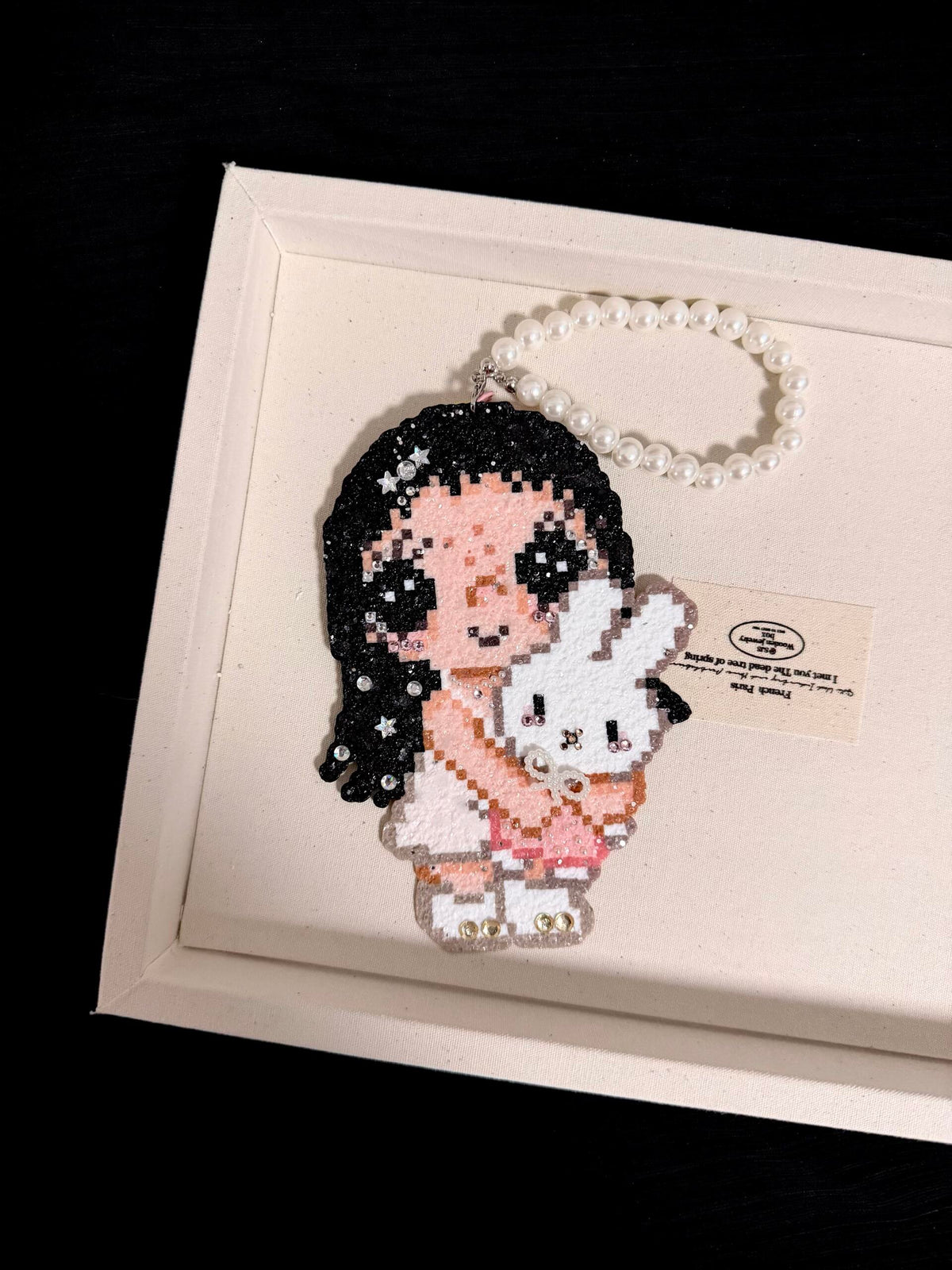 Second product photo of handmade pixel bead charm featuring a pink girl holding a white bunny